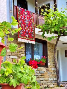 um tapete pendurado num edifício com flores numa janela em Къща за гости Песента на колелетата - Жеравна em Zheravna