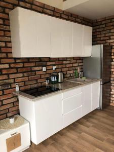 a kitchen with white cabinets and a brick wall at Zatoka Marina in Mechelinki +6 photos