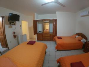Habitación de hotel con 2 camas y TV de pantalla plana. en Grand Hotel Paraiso Insular 1, en Puerto Baquerizo Moreno