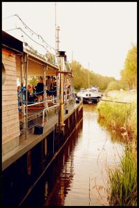 a boat traveling down a river with people on it at De Boot in Merkem