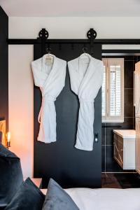 two white shirts hanging on a black wall in a bedroom at Gîte81 in Reeuwijk