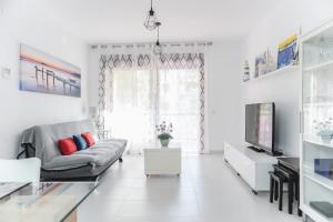 a white living room with a couch and a tv at Cambrils Beach & Sea in Cambrils
