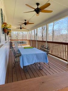 un porche cubierto con mesa y sillas en Beautiful 2 BR 1 BA Cabin in Blue Ridge Mountains: The Little White House en Martinsville