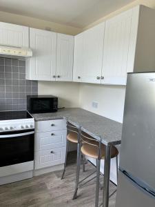 a kitchen with white cabinets and a table with two chairs at Willow Cottage in Kinloss