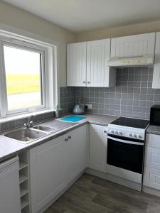 a kitchen with white cabinets and a sink and a window at Willow Cottage in Kinloss