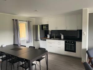 a kitchen with white cabinets and a table and chairs at På Taket Overnatting in Sørkjosen