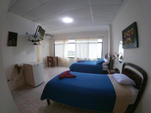 una camera d'albergo con due letti e una televisione di Grand Hotel Paraiso Insular 1 a Puerto Baquerizo Moreno