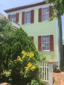a yellow house with a white fence and yellow flowers at Studio apartment at Historical House in Galveston