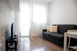 uma sala de estar com um sofá preto e uma televisão em Appartamenti Scrovegni em Pádua