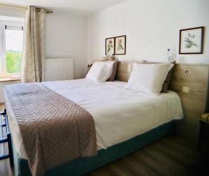 a bedroom with a large bed with white sheets and a window at B&B l'Aigrin in Durbuy