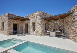 two people sitting at a table on the patio of a house at Santorini Sky, The Retreat in Pyrgos