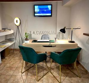 a desk with two green chairs and a television on a wall at Hostal La Canonja in Tremp