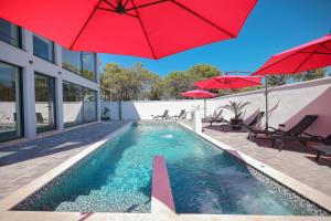Una piscina con sombrillas rojas en una casa. en Rhapsody in Green - Luxury villa in Zadar, en Crno