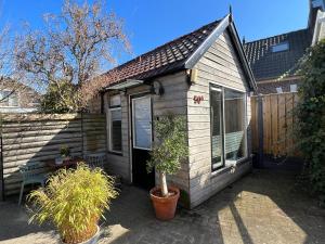 a small house with a potted plant in front of it at Sfeervol huisje, dichtbij bos en centrum in Apeldoorn