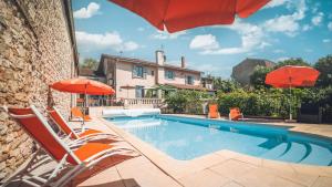 a swimming pool with chairs and umbrellas next to a house at Logis Hôtel Vuillot in Cuiseaux