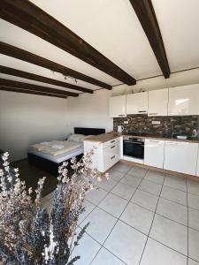 a kitchen with white cabinets and a bed in it at Penzion Levandule a Palava in Starovičky