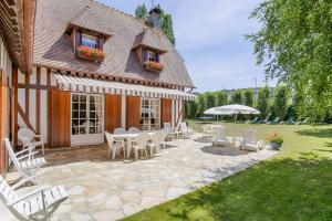 uma casa com um pátio com cadeiras e um guarda-sol em La Côte Fleurie - 5 Bdr - Garden & Jacuzzi - Tourgéville Plage em Deauville