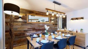 una sala da pranzo con tavolo, sedie e parete in legno di Élégant et Moderne avec Vue Montagne au Coeur de Paradiski - Garage - 8pers - 90m2 - Sabaudinha a Champagny-en-Vanoise