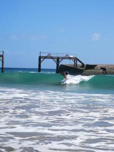 una persona montando una ola en una tabla de surf en el océano en Apto Punta Mujeres LAS ROSAS, en Punta Mujeres