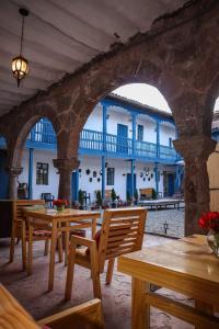 zewnętrzne patio z drewnianymi stołami i krzesłami oraz budynek w obiekcie CASA CRISTOBAL Siete Cuartones CASONA COLONIAL w Cuzco