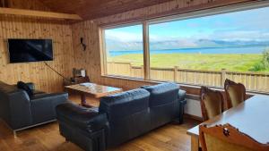 Una sala de estar con sofás y una gran ventana. en Glass House with Private River & 360° Views, en Stapi