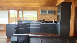 una cocina con armarios azules y un sofá en una habitación en Glass House with Private River & 360° Views, en Stapi