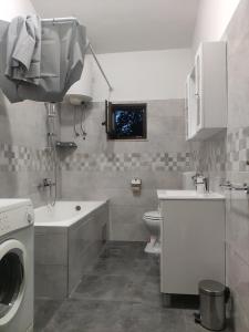 a bathroom with a toilet and a sink and a washing machine at Eros Rooms in Split