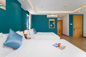 a bedroom with two beds and a blue wall at Merry Land Hotel Da Nang in Danang