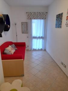 a living room with a red couch and a window at Casa Corallo Muravera Appartamento Centralissimo due camere letto cucina e soggiorno nuovo letto matrimoniale e singoli Aria condizionata Parcheggio interno Coperto ideale x 2 o 3 moto in Muravera