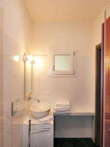 Baño blanco con lavabo y espejo en Residence Casa Di Caccia, en Marina di Bibbona