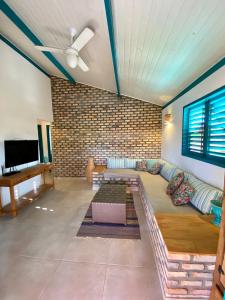 a living room with a couch and a brick wall at Wind Nomade House - São Miguel do Gostoso in São Miguel do Gostoso +27 photos