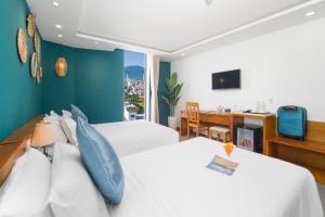 a hotel room with two beds and a desk at Merry Land Hotel Da Nang in Danang