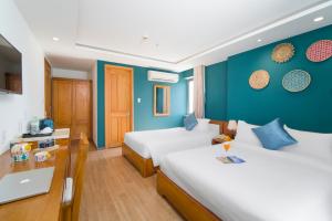 a bedroom with two beds and a blue wall at Merry Land Hotel Da Nang in Danang
