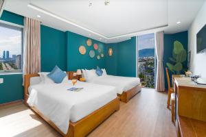 two beds in a room with blue walls at Merry Land Hotel Da Nang in Danang
