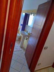 a door to a bathroom with a sink and a toilet at Casa Corallo Muravera Appartamento Centralissimo due camere letto cucina e soggiorno nuovo letto matrimoniale e singoli Aria condizionata Parcheggio interno Coperto ideale x 2 o 3 moto in Muravera