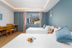 a hotel room with two beds and a desk and a window at Merry Land Hotel Da Nang in Danang