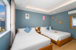 two beds in a room with blue walls at Merry Land Hotel Da Nang in Danang