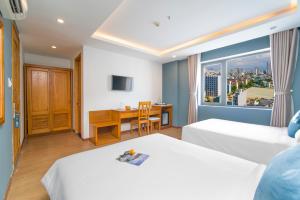 a hotel room with two beds and a desk at Merry Land Hotel Da Nang in Danang