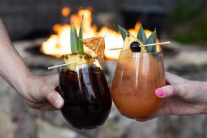 two people holding up two cocktails in front of a fire at Admiral's Inn Resort in Ogunquit
