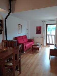 sala de estar con sofá rojo y mesa en CHECK-IN CASAS Apto Cercedilla, en Cerler