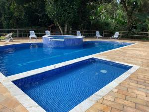 a blue swimming pool with chairs at excelente casa em Juquehy in São Sebastião