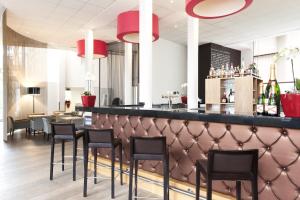 a restaurant with black chairs and a bar with red lights at Novotel Brugge Centrum in Bruges