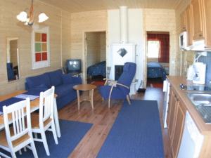 a kitchen and a living room with a blue couch at Wanha Pappila Cottages in Simoniemi