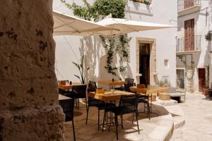 un patio con tavoli, sedie e ombrellone di Aquamarea a Polignano a Mare