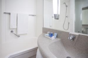 a bathroom with a sink, mirror, and toilet at Novotel Brugge Centrum in Bruges