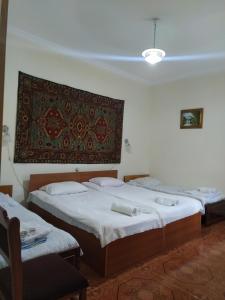 - 2 lits dans une chambre avec un tapis sur le mur dans l'établissement IRIS B&B in DEBED CANYON, à Alaverdi
