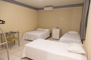 Cette chambre comprend deux lits et une table avec chauffage. dans l'établissement Canadá Hotel, à Rio Verde