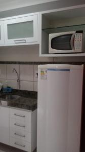 uma cozinha branca com um micro-ondas e um frigorífico em Terrazzo PontaNegra Flat Vista Mar Apto 211 em Natal