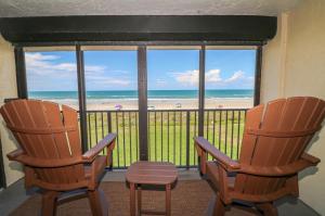 2 sillas frente a una ventana con vistas a la playa en Sand Dollar Two 202, en St. Augustine