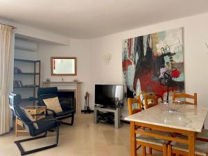 sala de estar con mesa, sillas y TV en Beautiful Villa with terrace & garden, en Ferragudo